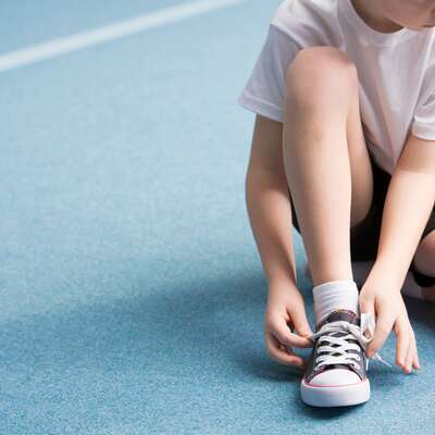 Young child tying up their shoe laces before PE